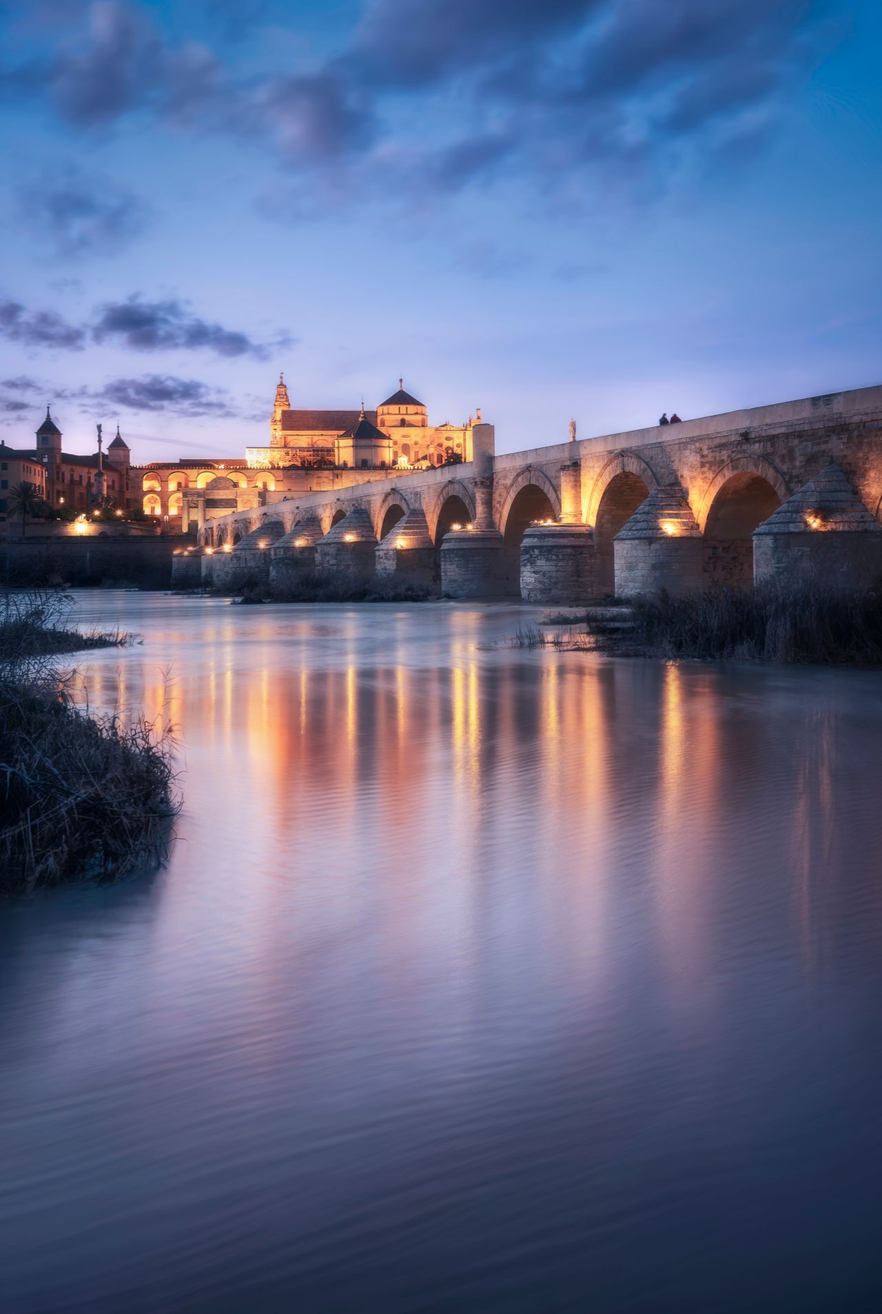 Ccrepúsculo del Puente Romano y el río Guadalquivir en Córdoba